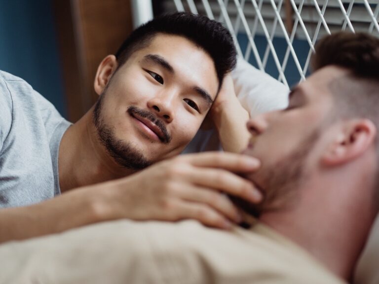 Gay couple caressing in bed